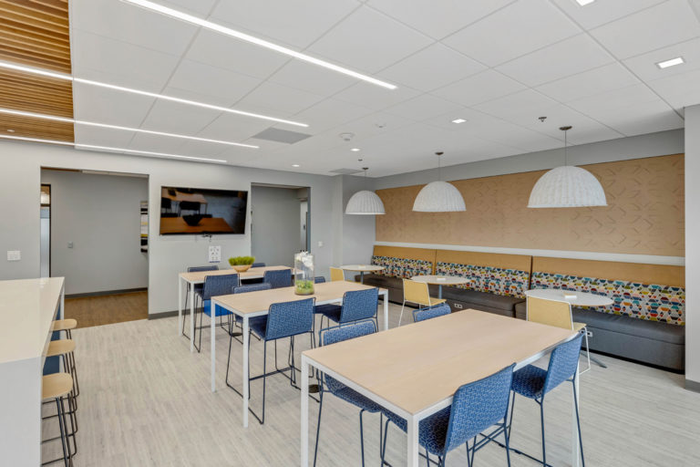 Modern office interior with open seating, casual meeting areas, and contemporary lighting.