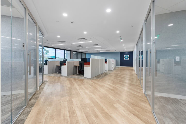 Modern office interior with workstations, glass walls, and wood flooring | LAY Construction.