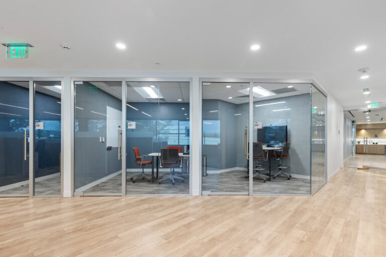 Bright modern office interior with glass conference rooms and wood flooring for commercial construction.