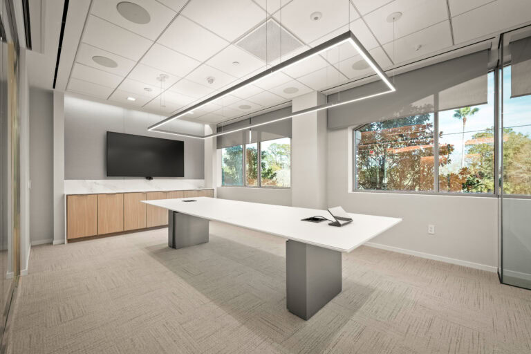 Modern office conference room with large windows, sleek design, and contemporary lighting.