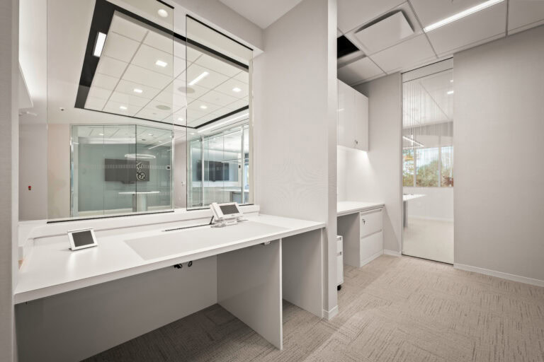 Modern office interior with sleek white desks and glass partitions for professional workspace design.