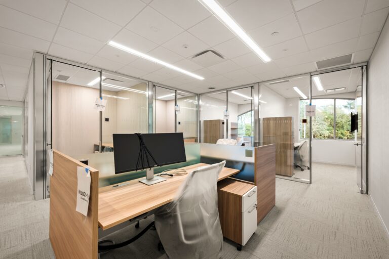 Modern office workspace with glass partitions and ergonomic furniture for commercial office design and construction.