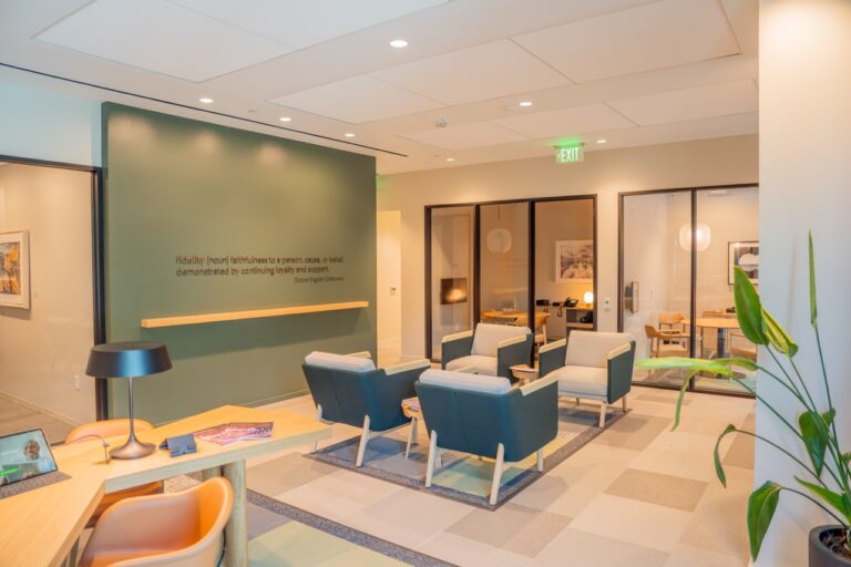 Modern office lounge with comfortable chairs and a green accent wall.