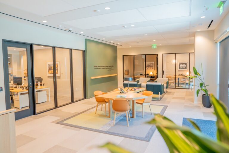 Modern office interior with meeting area and glass walls, bright lighting, and contemporary decor.